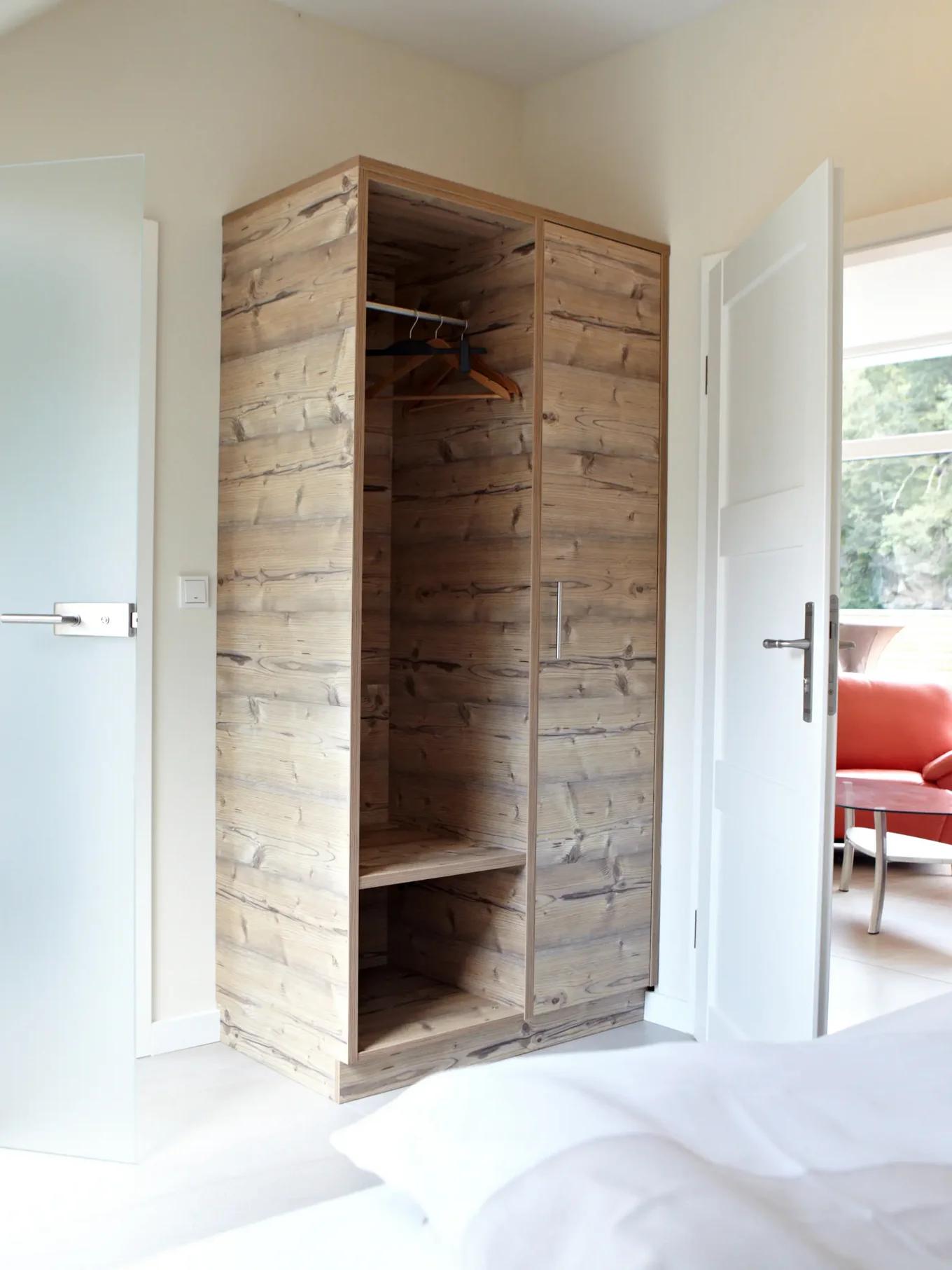 Hotelzimmer mit Holzschrank, einer weißen Tür und einer Tür in Milchglasoptik